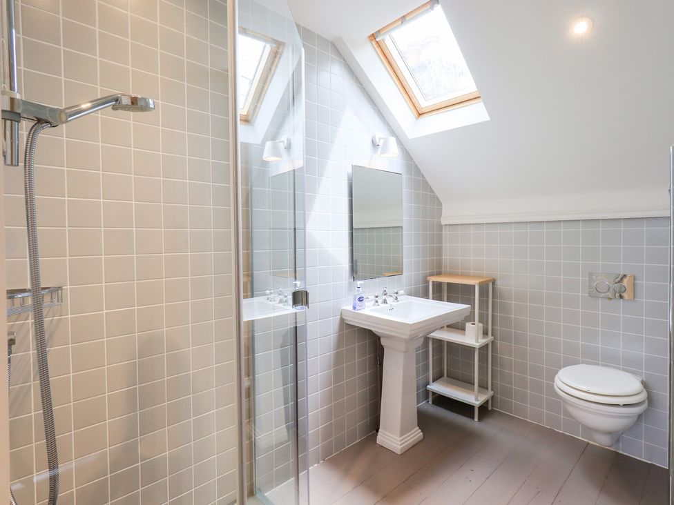 A bathroom with shower, sink, toilet, and mirror at Little Ellers in Portinscale near Keswick