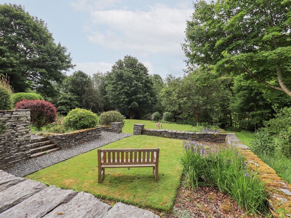 A garden with a bench and stone wall at Little Ellers in Portinscale near Keswick