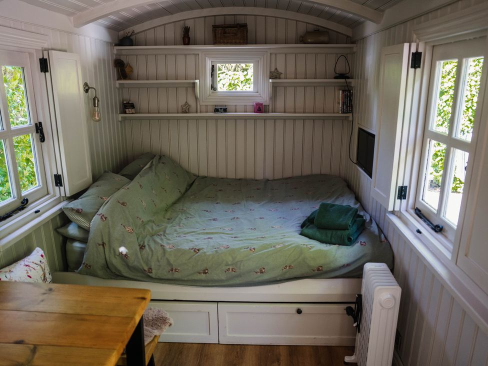 A sleeping area with a bed and shelves at The Snug in Longtown