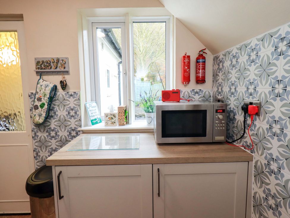 A kitchen with a microwave and fire extinguishers at Foresters Cottage Satterthwaite