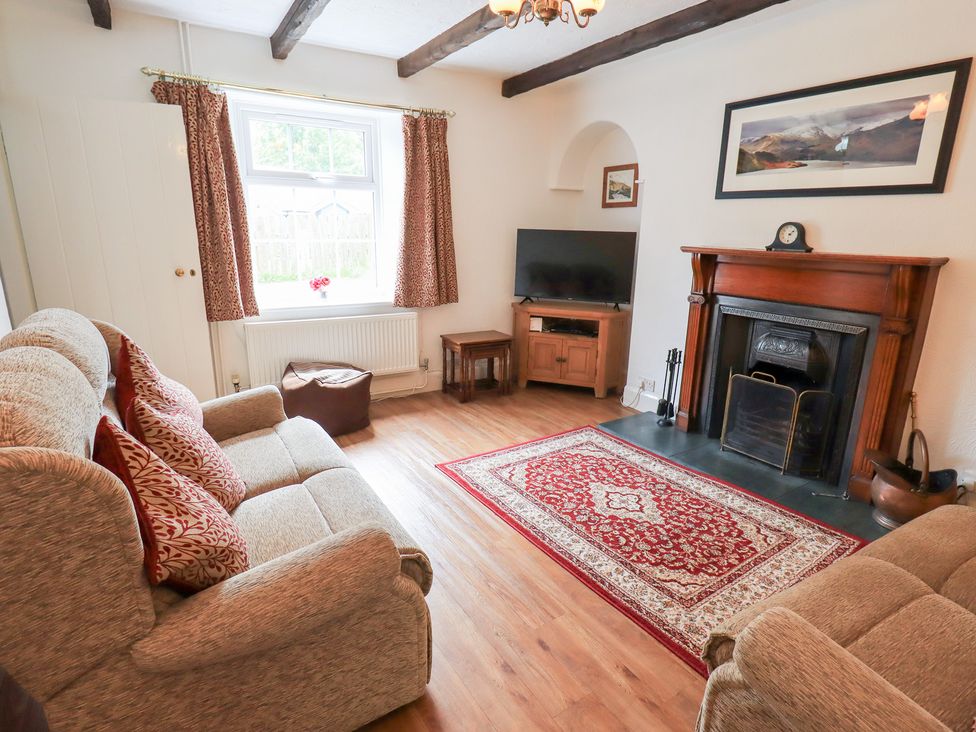 A sitting room with a sofa and fireplace at Millcroft in Glenridding