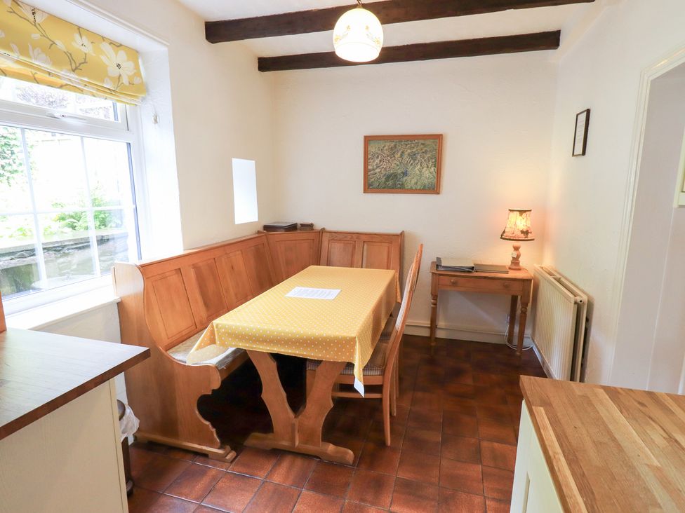 A dining room with a table and benches at Millcroft in Glenridding