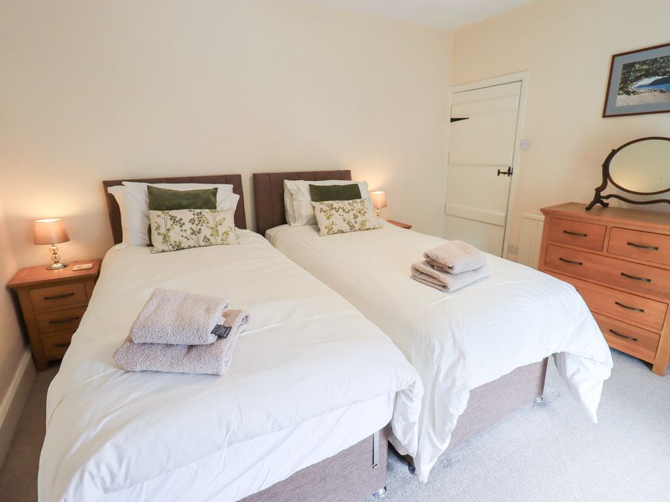 A bedroom with twin beds and a dresser at Millcroft in Glenridding