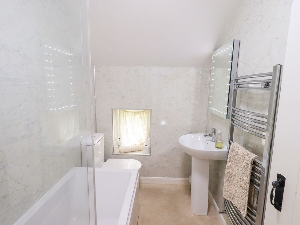 A bathroom with a bathtub, toilet, and sink at Millcroft in Glenridding