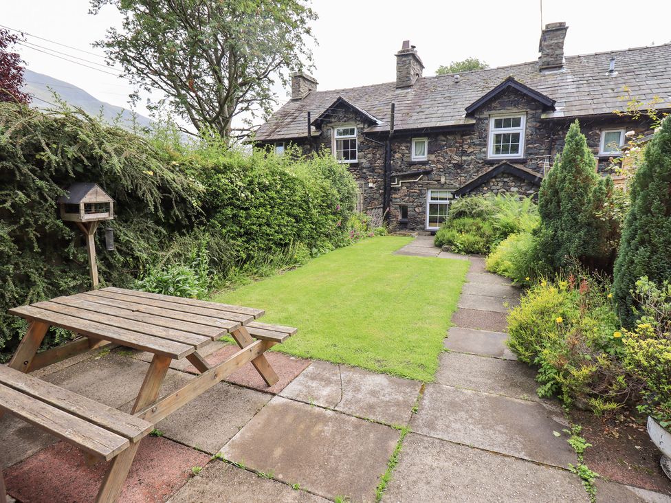 A garden with a stone wall, picnic table and birdhouse at Millcroft Glenridding