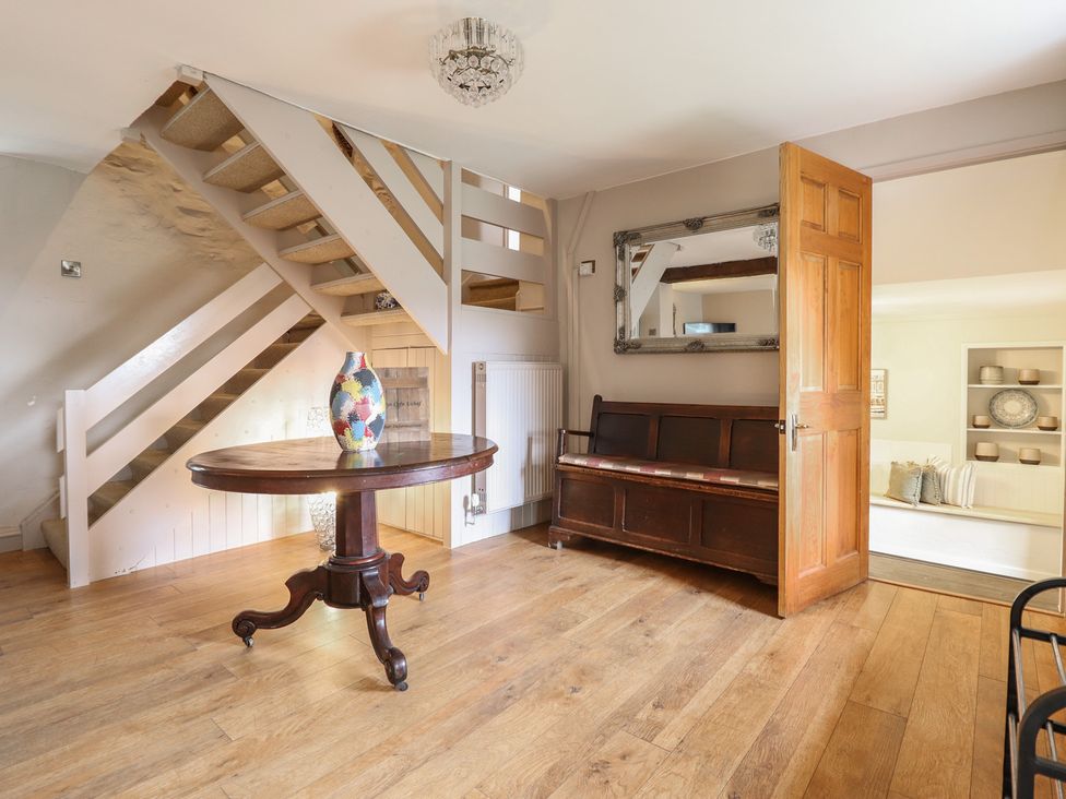 A hallway with a staircase and a table at Cefn Uchaf Cottage in Llanbedr