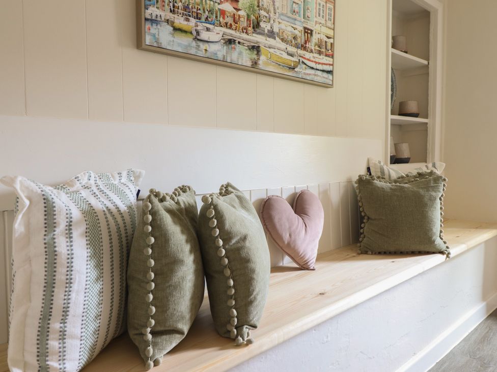 A bench with pillows and a painting at Cefn Uchaf Cottage Llanbedr