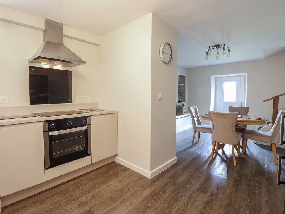 A kitchen with an oven and dining table at Cefn Uchaf Cottage in Llanbedr