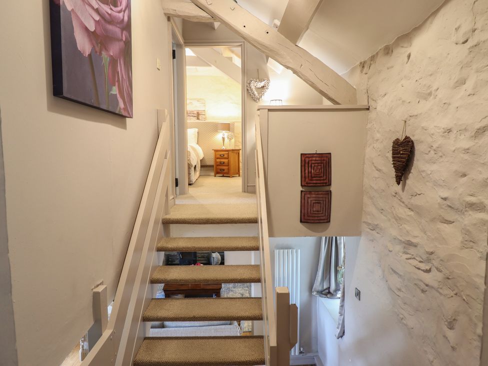 A hallway with stairs and wall art at Cefn Uchaf Cottage in Llanbedr