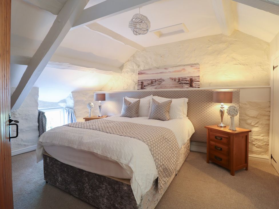 A bedroom with a bed and lamps at Cefn Uchaf Cottage in Llanbedr