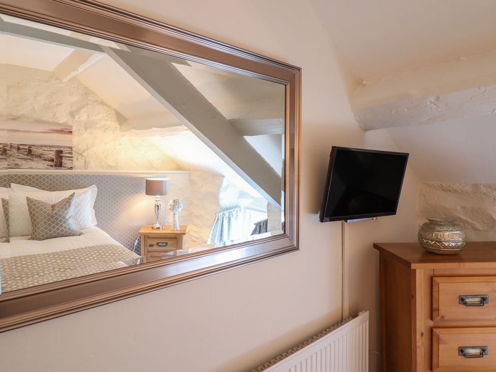 A bedroom with a bed and television at Cefn Uchaf Cottage Llanbedr