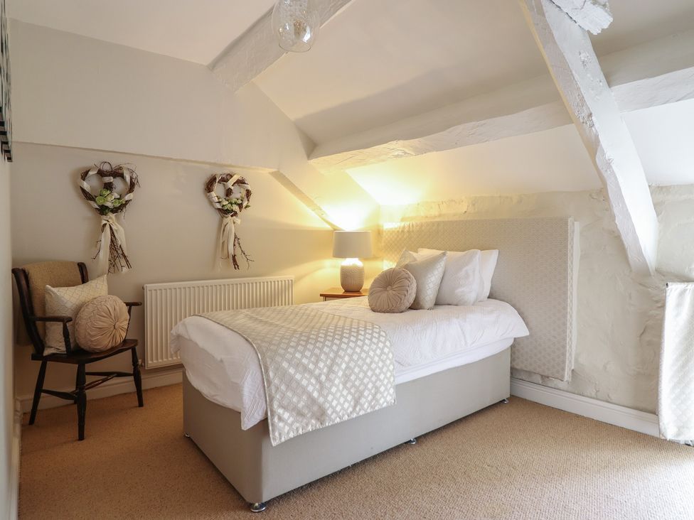 A bedroom with a bed and lamp at Cefn Uchaf Cottage in Llanbedr