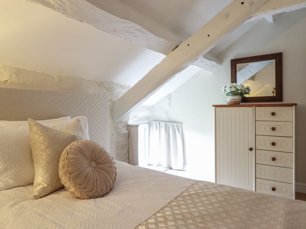 A bedroom with a bed and dresser at Cefn Uchaf Cottage Llanbedr