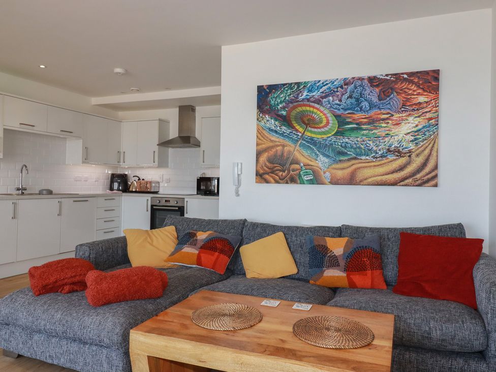 A living room with a sofa and kitchen area at The View in Newquay