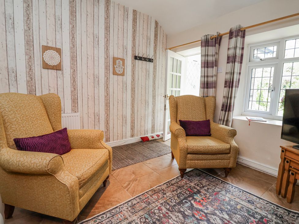 A living room with armchairs and a television at Riverlea in Dyserth