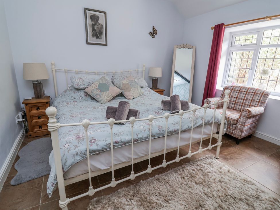 A bedroom with a bed and a chair at Riverlea in Dyserth