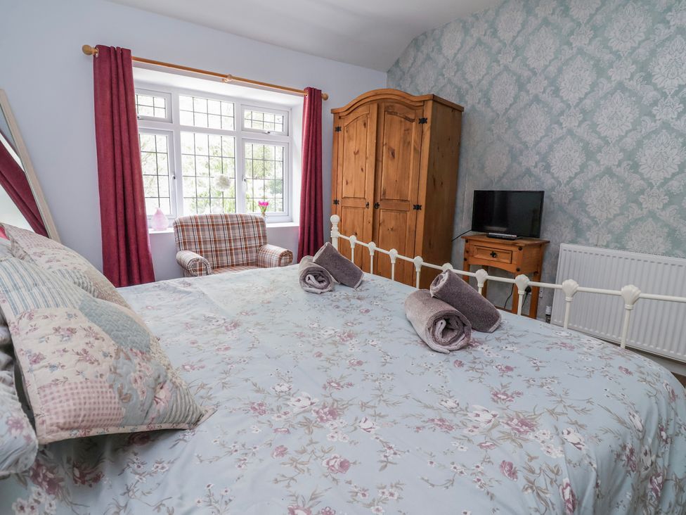 A bedroom with a bed and wardrobe at Riverlea in Dyserth