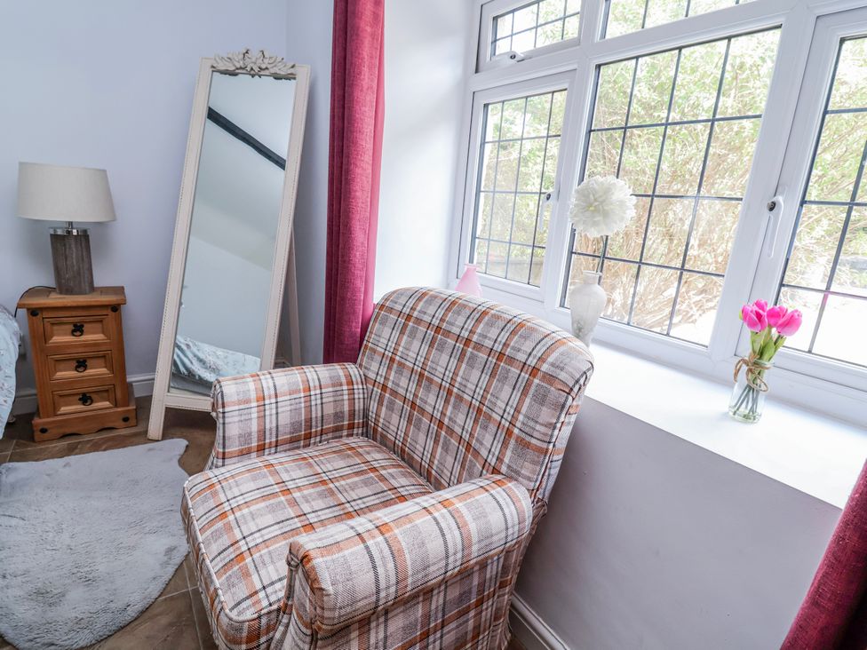A living room with an armchair and a mirror at Riverlea in Dyserth