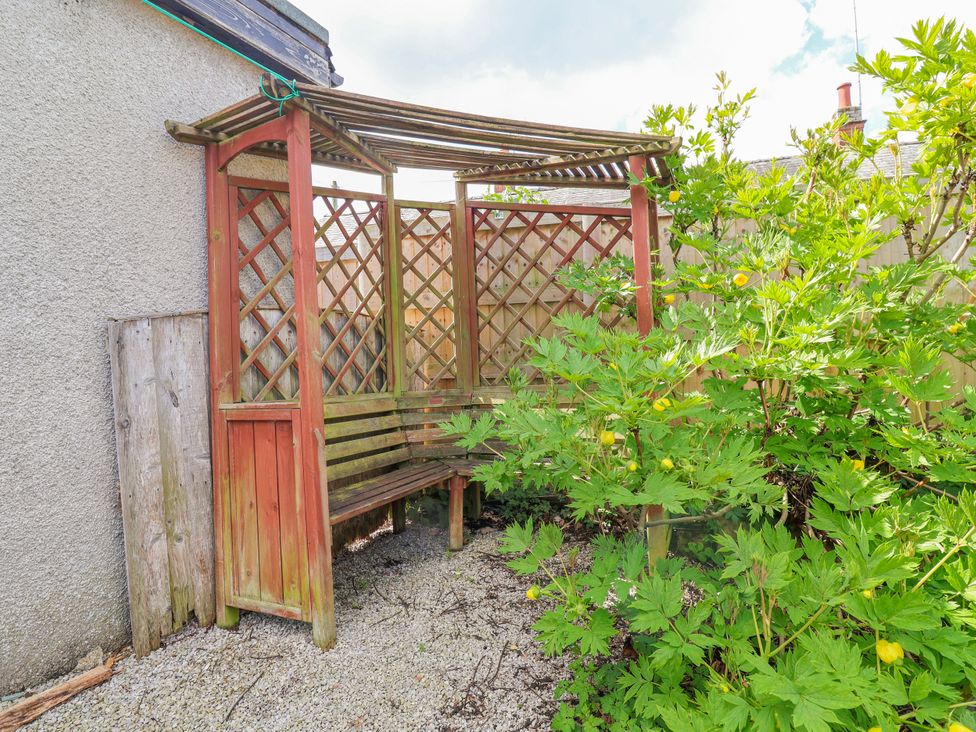 A garden with a bench and lattice structure at Riverlea in Dyserth