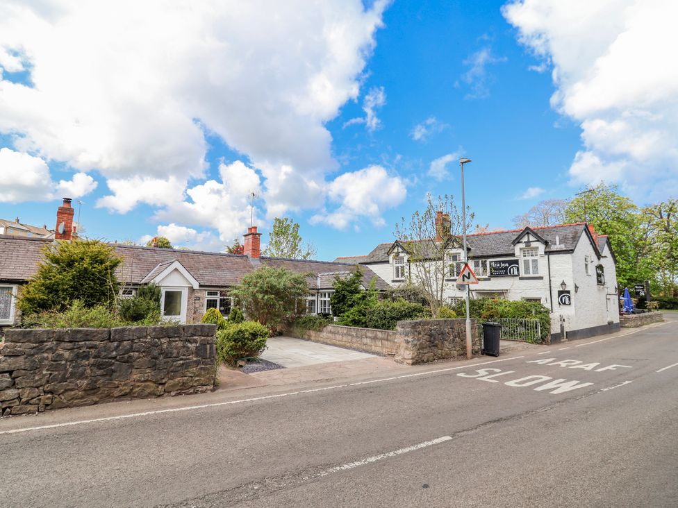 A building with trees and a stone wall near the road at Riverlea Dyserth
