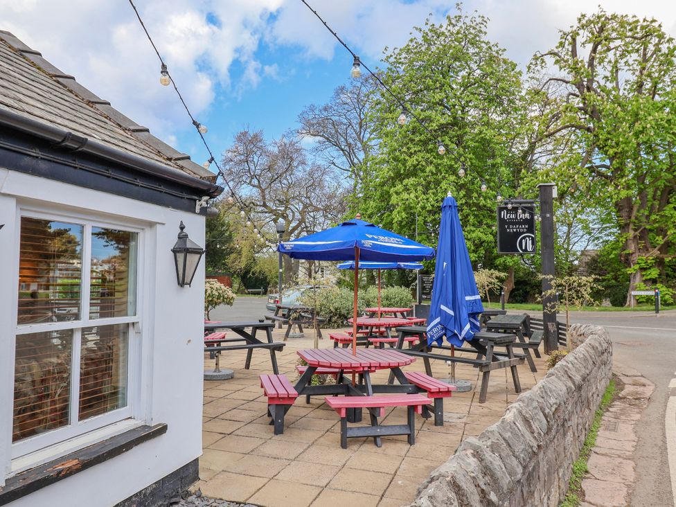 An outdoor seating area with tables and umbrellas at Riverlea in Dyserth