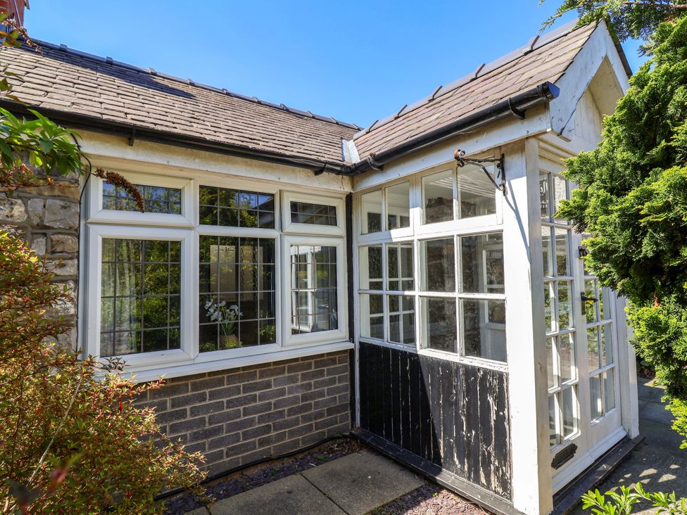 A conservatory with large windows and a door at Ty Cerrig in Dyserth