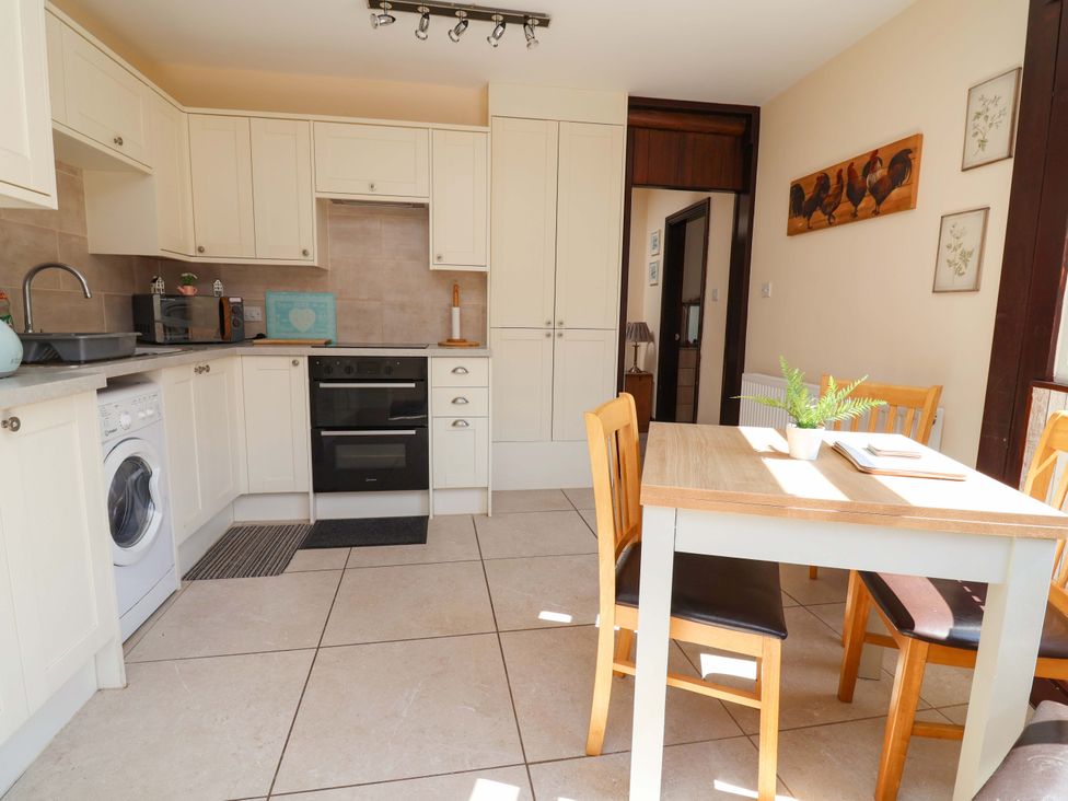 A kitchen with cabinets, appliances and a dining table at Ty Cerrig in Dyserth
