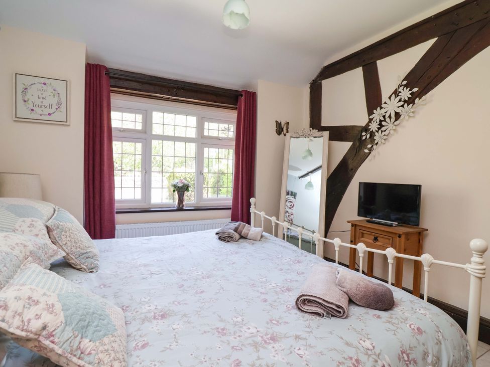 A bedroom with a bed, window, mirror, and tv at Ty Cerrig in Dyserth