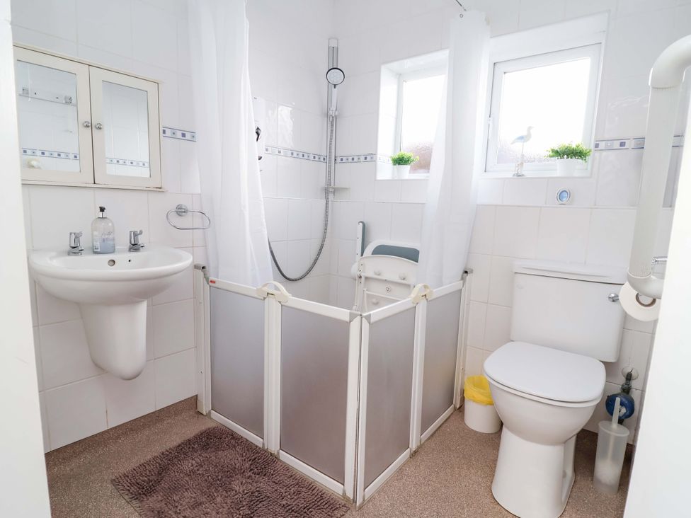 A bathroom with a sink, toilet, and shower at Ty Cerrig in Dyserth