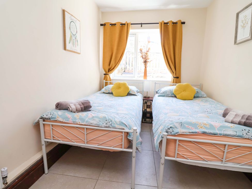 A bedroom with two beds and a window at Ty Cerrig in Dyserth