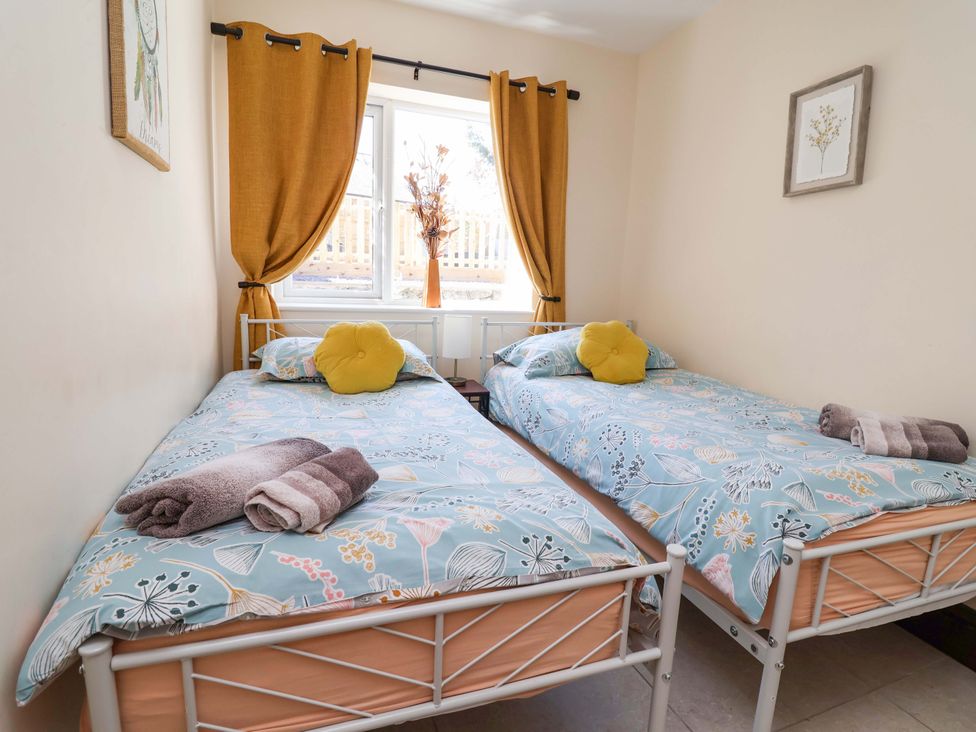 A bedroom with two beds and a window at Ty Cerrig in Dyserth