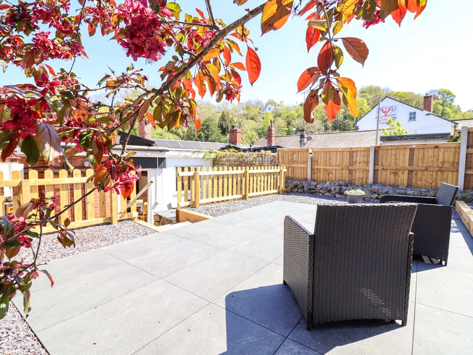 A garden with chairs and a flowering tree at Ty Cerrig in Dyserth