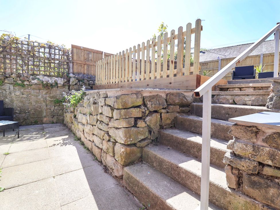 A garden with stone steps and a wooden fence at Ty Cerrig in Dyserth