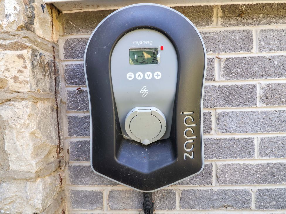 An electric vehicle charger mounted on a stone wall at Ty Cerrig in Dyserth