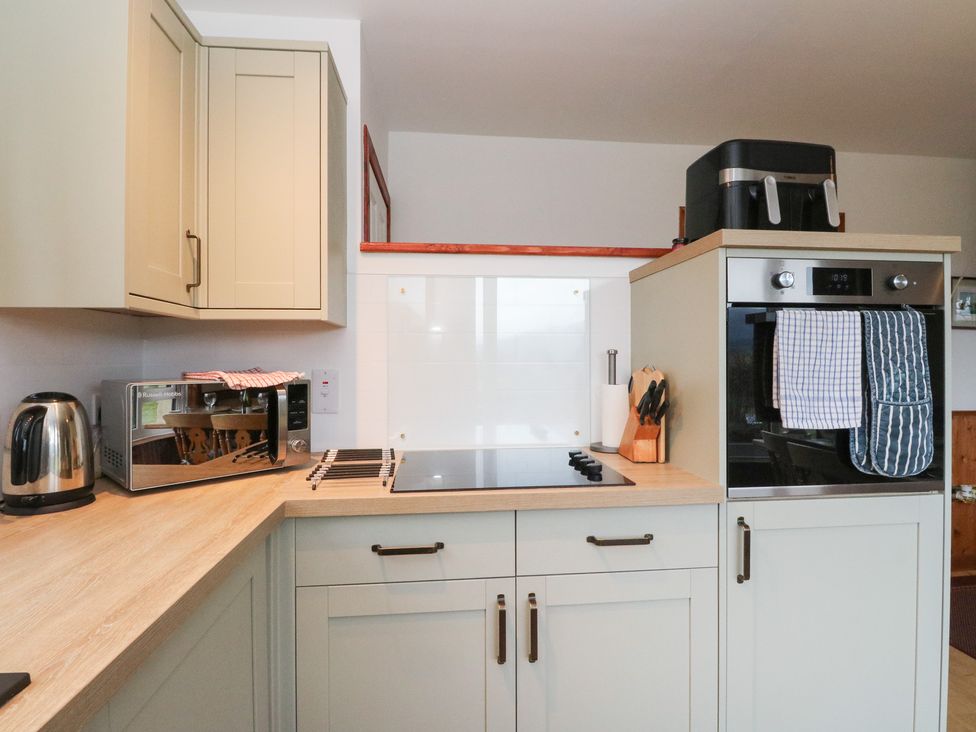 A kitchen with cabinets, oven, cooktop, and microwave at Alba Ben View in Spean Bridge