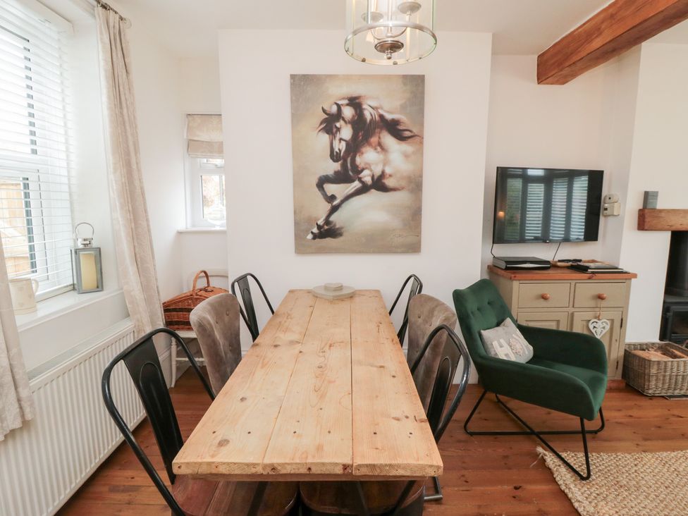 A dining room with a wooden table and chairs at Harriet's Cottage in Briggswath