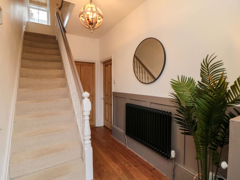 A hallway with a staircase and a mirror at Harriet's Cottage in Briggswath
