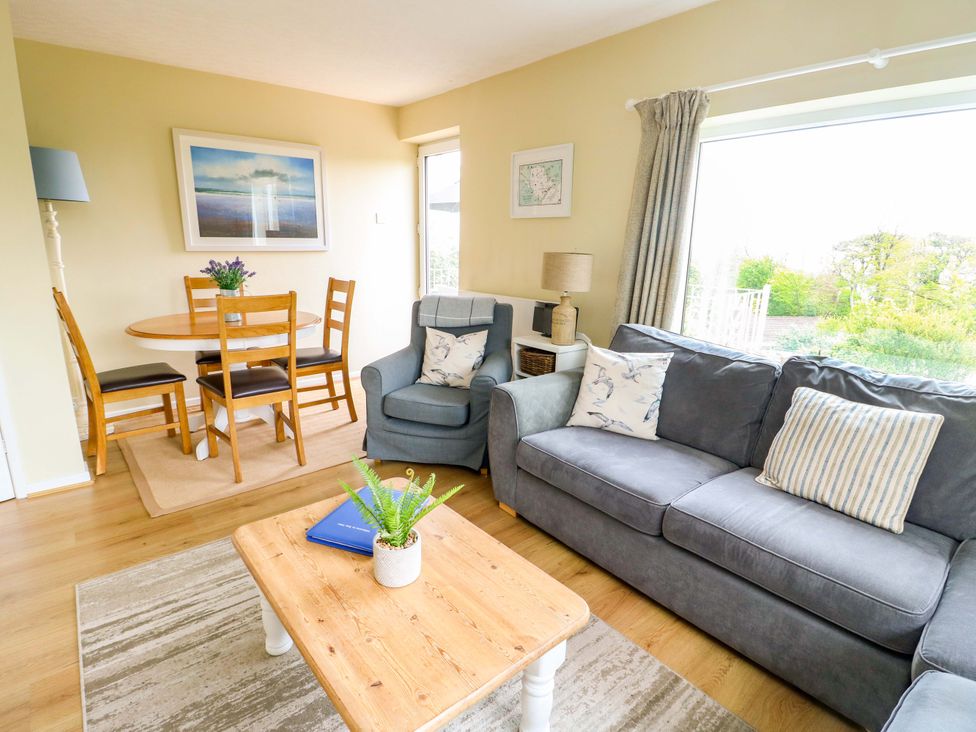 A living room with a sofa and dining area at Sea View in Benllech