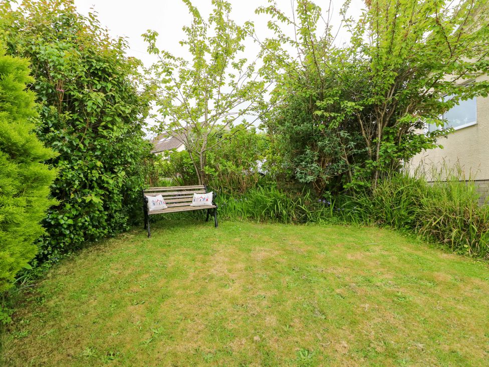 A garden with a bench among trees and bushes at Sea View in Benllech