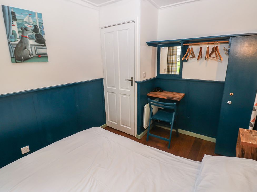 A bedroom with a bed, desk, and door at Driftwood in Roch