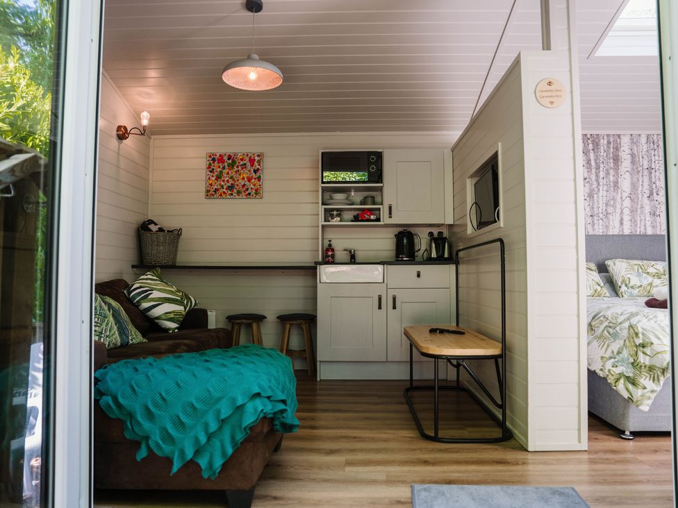 A living room with a sofa and kitchenette at Reflection in Longtown