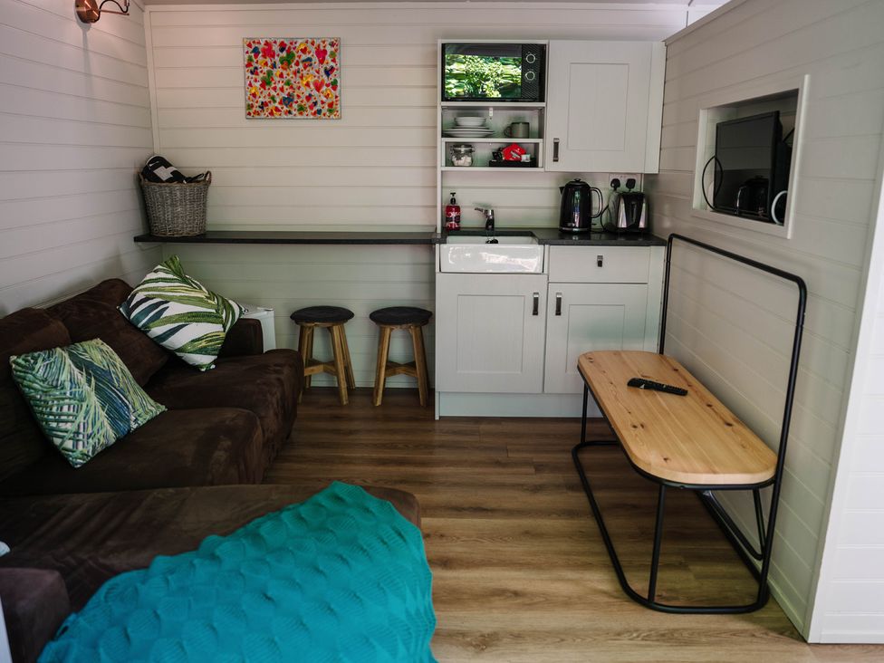A living room with a sofa and kitchenette at Reflection in Longtown