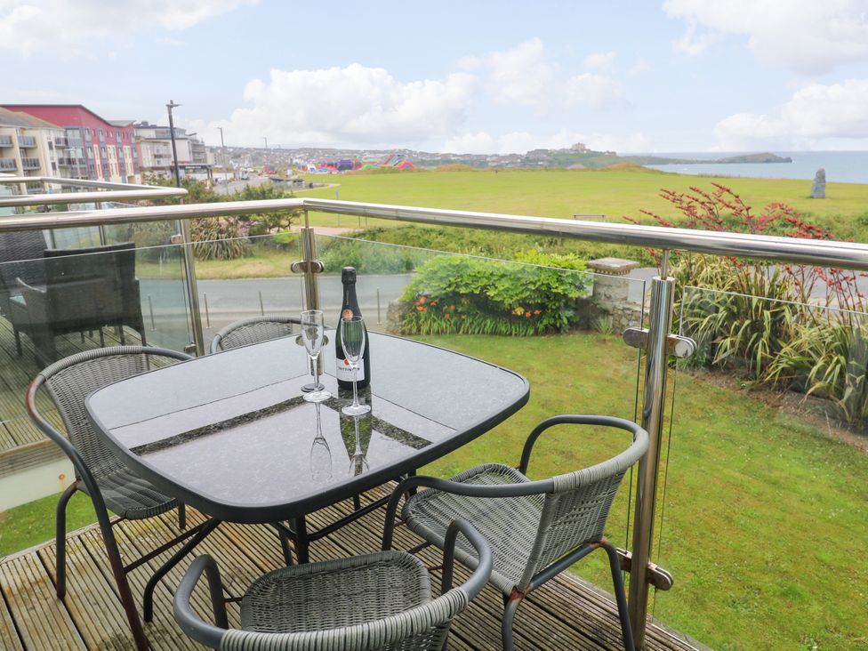 A balcony with a table and chairs overlooking a grassy area at Ocean Seven in Newquay