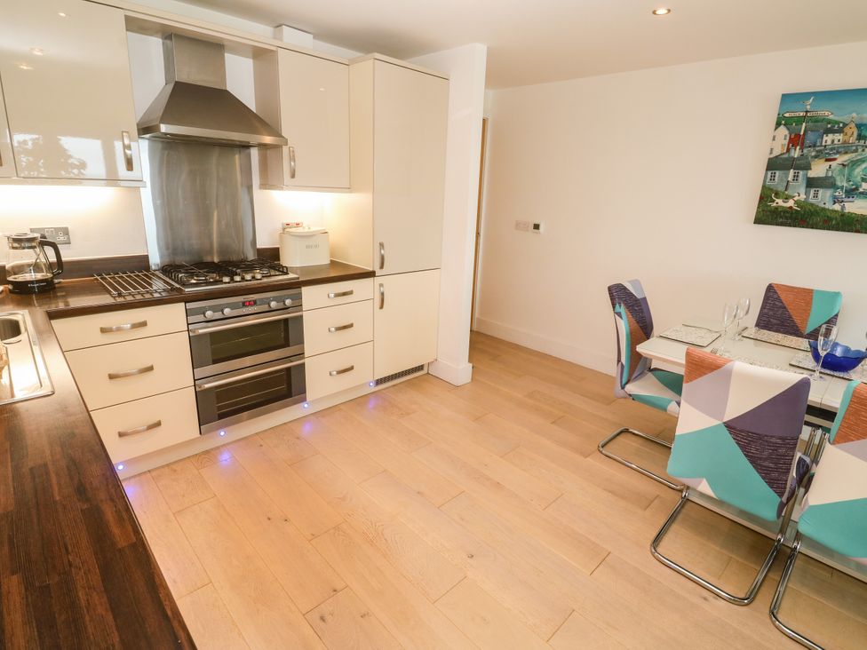 A kitchen with a stove, oven, sink, and dining area at Ocean Seven in Newquay