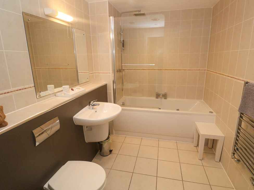A bathroom with a bathtub and shower next to a sink and toilet at Ocean Seven in Newquay