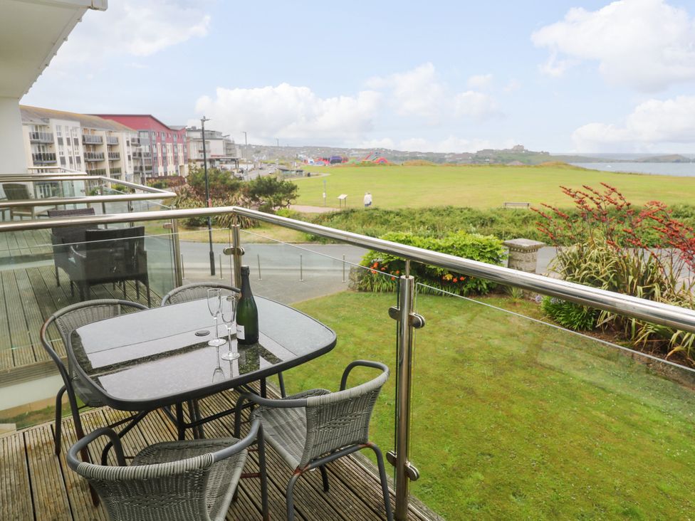 A balcony with a table and chairs overlooking a grassy area at Ocean Seven in Newquay