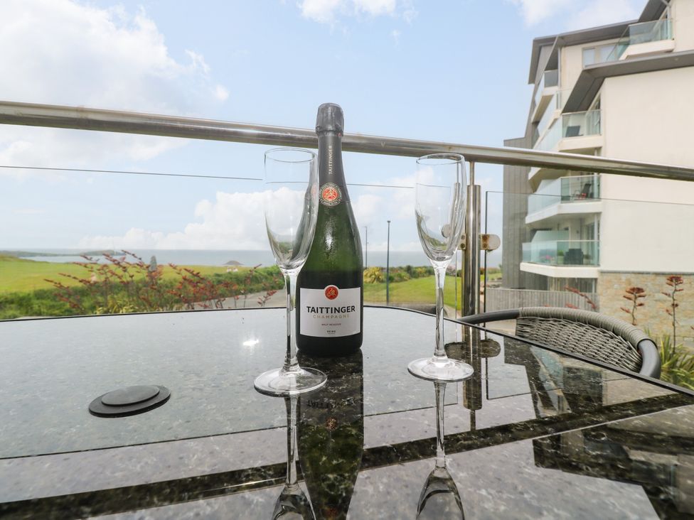 A bottle of champagne and glasses on a table with a view at Ocean Seven in Newquay