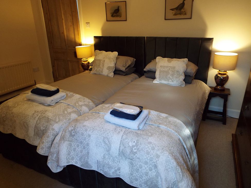 A bedroom with twin beds and bedside lamps at Milltown House in Turriff