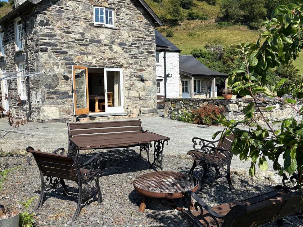 An outdoor seating area with a stone house at Peniarth Ganol in Tywyn