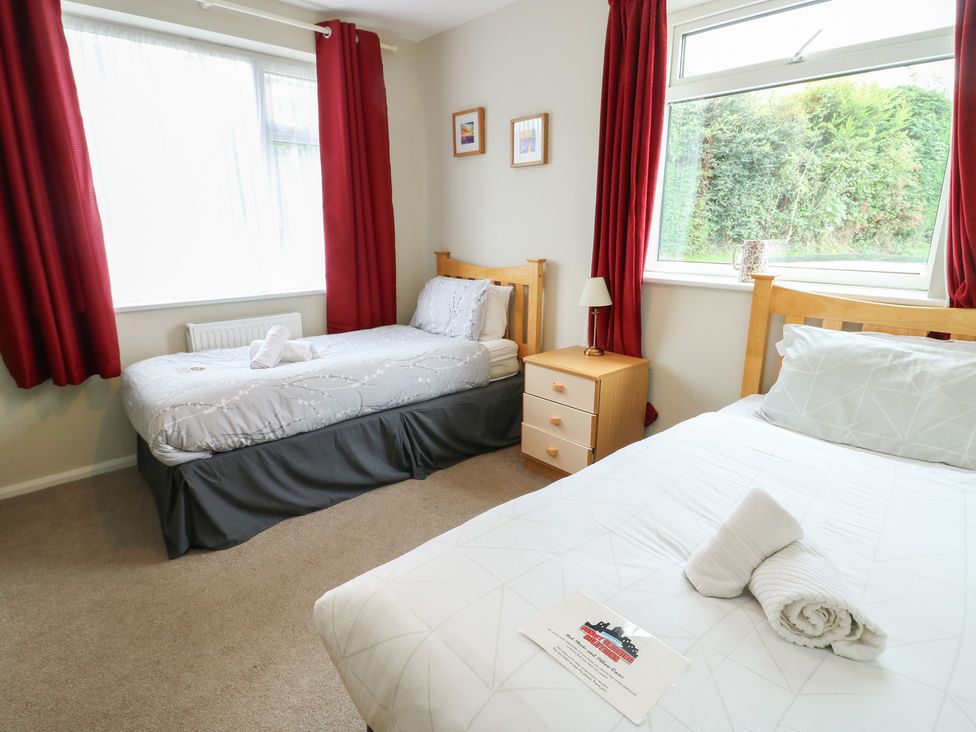 A bedroom with two beds and a window at Awelon in Rhos-On-Sea